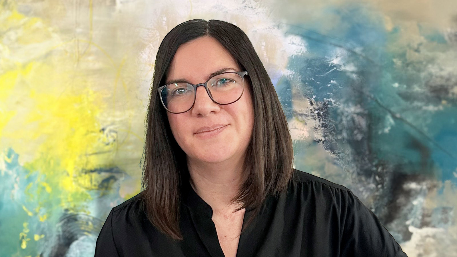Frau mit Brille und dunklem Haar vor einem bunten abstrakten Hintergrund.